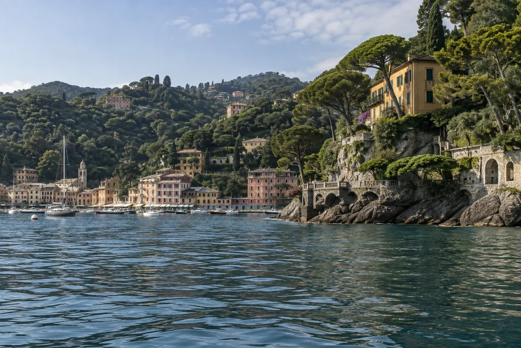 Ligurian coast between Portofino and Santa Margherita seen from water, wooded slopes and warm waterfront buildings, quiet natural daylight